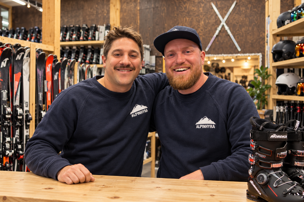 Philip och Jonas bakom disken hos Alpinhyra, med skidor och pjäxor i bakgrunden.